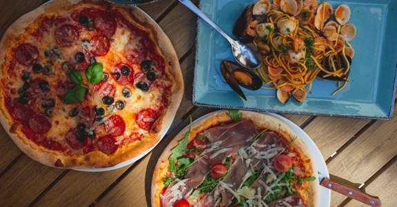 Italienische Pizza mit frischem Salat und Pasta auf einem gedeckten Restauranttisch